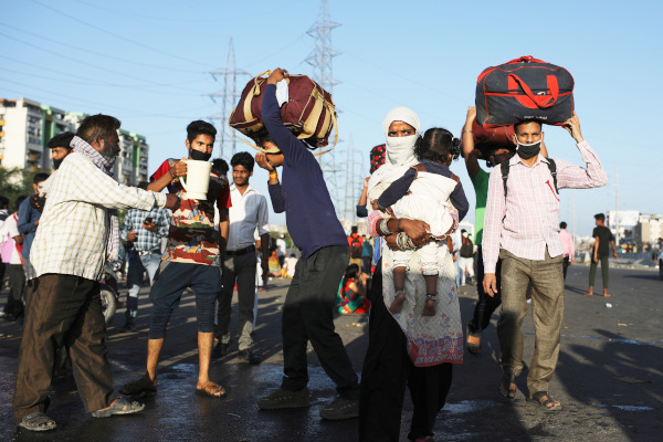Moradores locais fornecem água potável a trabalhadores migrantes indianos. Nova Deli, Índia, 28 de março. (Foto: AP)