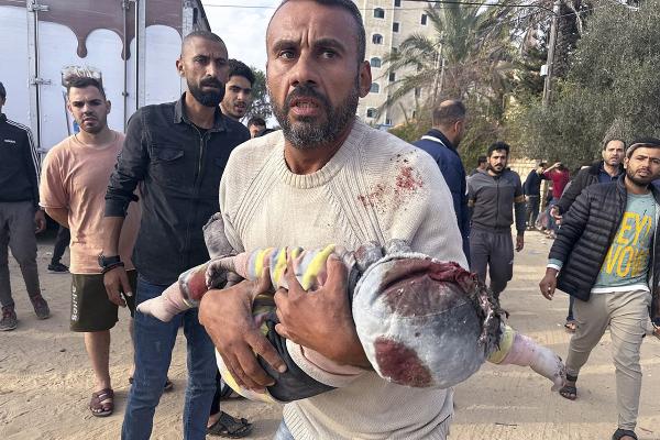 Um palestino resgata uma criança ferida por um ataque israelita no centro da Faixa de Gaza, 28 de dezembro de 2023